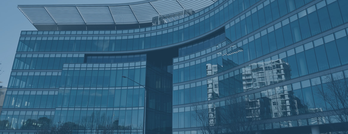Modern glass office building exterior with blue-toned reflections against a dark sky, conveying a sleek retail atmosphere