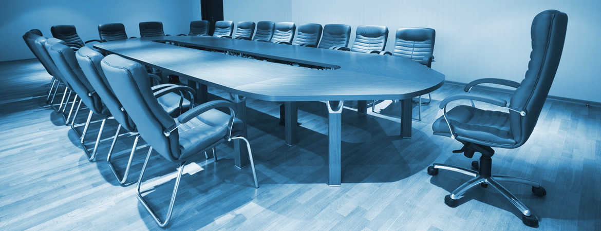 Empty conference room with a long oval table and leather chairs in a blue-toned monochrome filter, suggesting a professional retail showroom