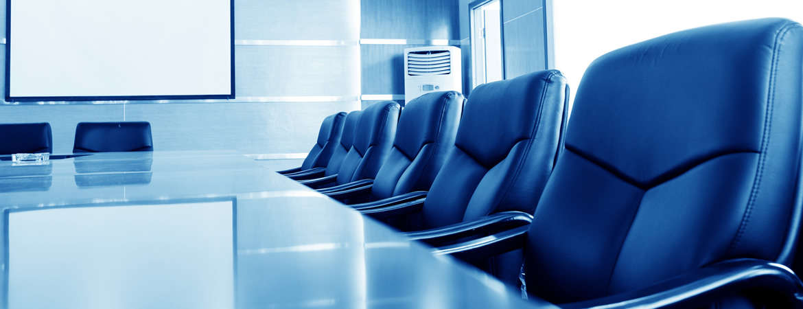 Empty boardroom with black leather chairs along a glossy table and a blank projection screen, in a blue-toned corporate style
